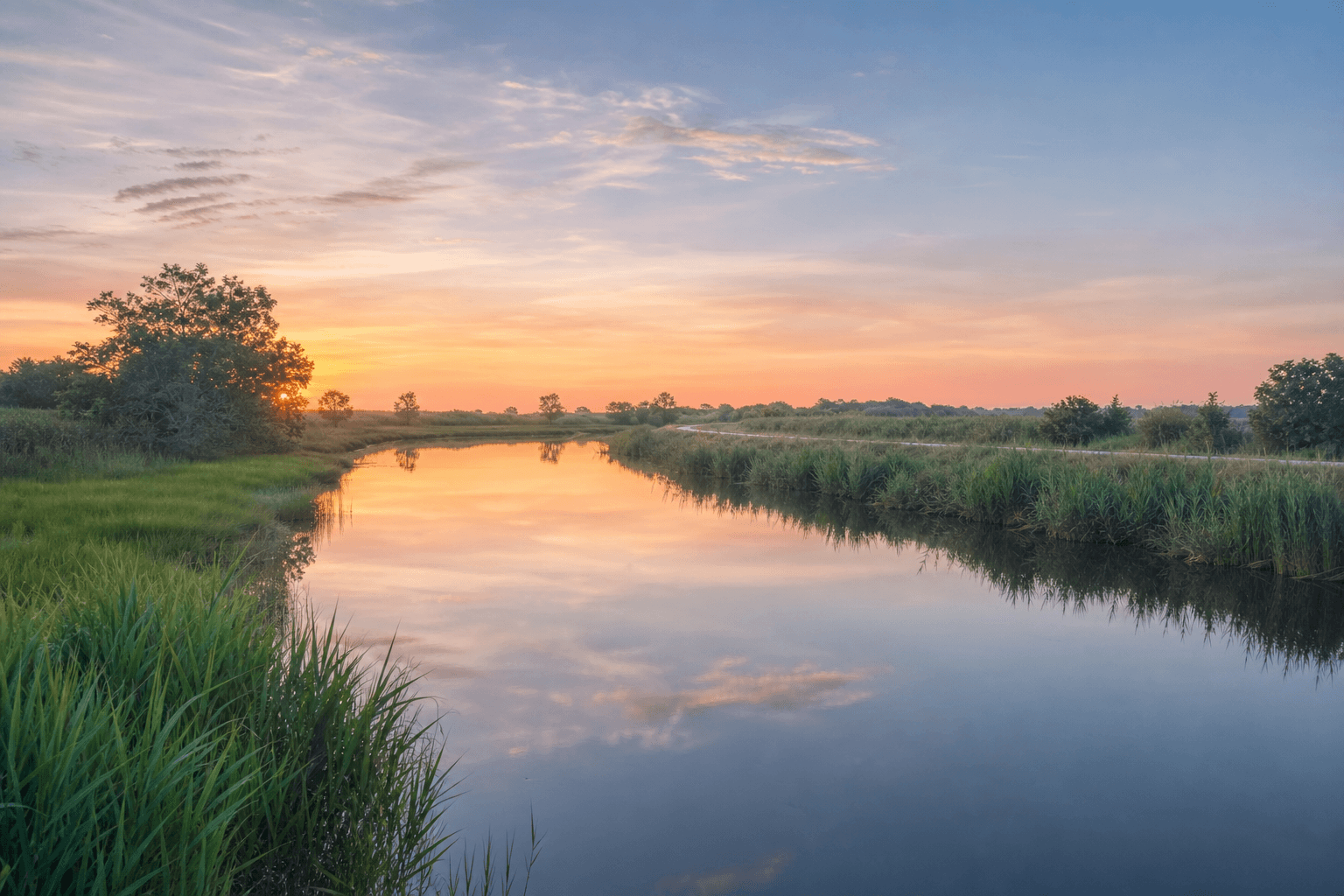 Delaware wetlands and waterway at sunset with calm reflections and green marshlands