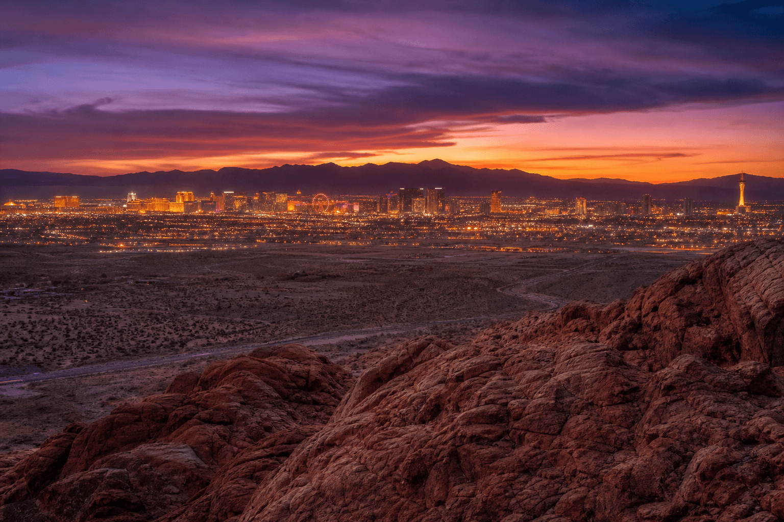 Las Vegas Strip glowing at twilight with Nevada desert and red rock formations in foreground