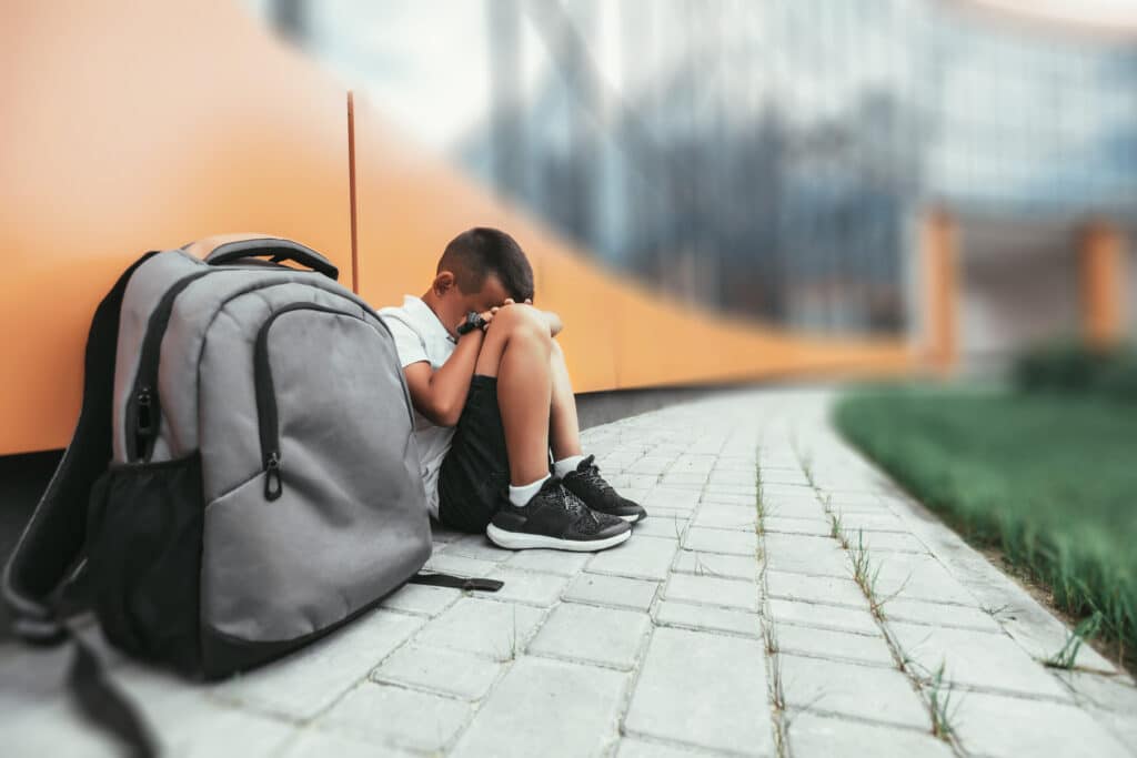 Child with backpack sitting in depression