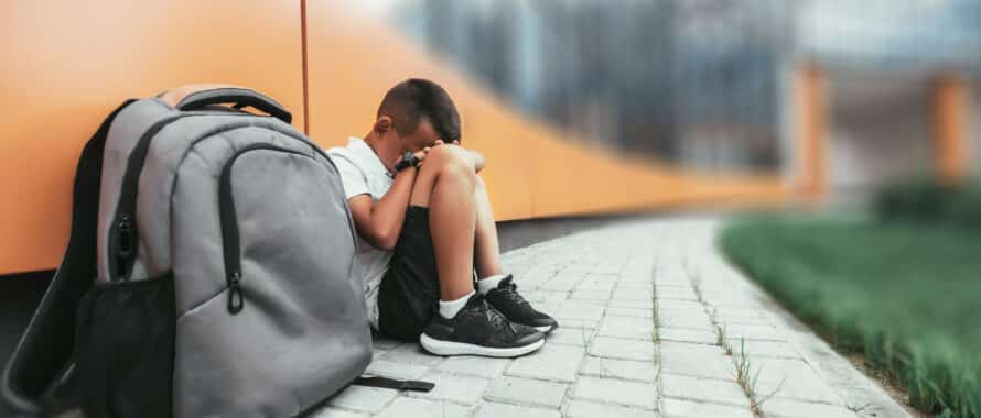 Child with backpack sitting in depression